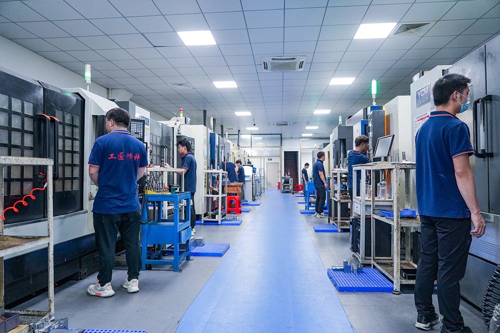 Mold machining shop with rows of CNC machines and toolmakers at work